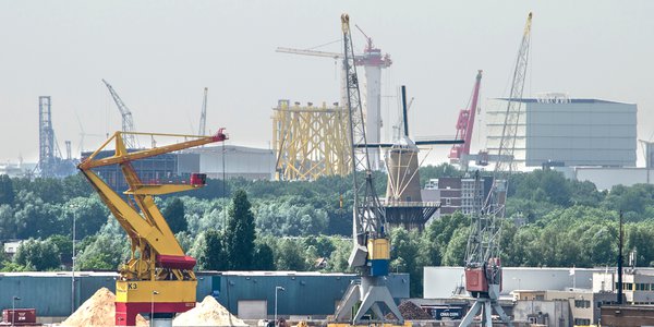 Uitzicht op de industriegebieden van Merwe Vierhavens in Rotterdam en Schiedam, met havenkranen en ander materieel, evenals een traditionele windmolen door Frans Blok (bron: Shutterstock)
