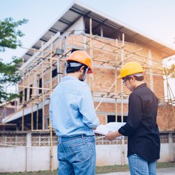 Two engineering man with helmet and paper work are discussing about the project over construction site background. door Freedom Studio (bron: Shutterstock)
