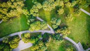 Bovenaanzicht luchtfoto van vliegende drone van een stadspark met wandelpad en groene zonebomen in de avondtijd door Aleksandrs Muiznieks (bron: Shutterstock)