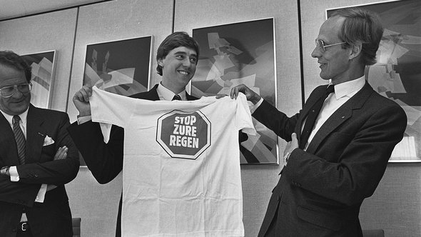 Oude en nieuwe minister van Economische Zaken ; nieuwe minister van VROM Ed Nijpels (l) krijgt t-shirt van voorganger Winsemius door Rob Bogaerts / Anefo (bron: Wikimedia Commons)