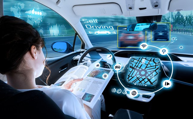 jonge vrouw het lezen van een boek in een autonome auto. bestuurderloze auto. zelfrijdend voertuig. heads up display. automotive technologie. door metamorworks (bron: Shutterstock)