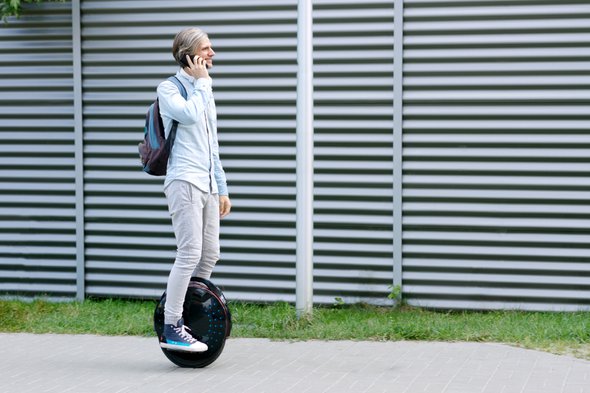 Modern young adult male businessman student freelancer riding driving on ecological electric transport futuristic eco electric unicycle scooter, balancing electric wheel with smartphone. Eco planet. door Monstar Studio (bron: Shutterstock)