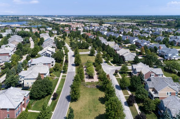 Aerial view of a neighborhood in suburban Chicago with homes on either side of a parkway. door pics721 (bron: Shutterstock)
