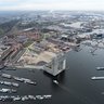 Luchtfoto van woningbouwlocatie in de Houthavens. Wolkenkrabber appartementengebouw Pontsteiger aan de voorzijde met boten in de haven.