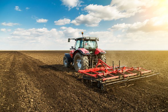 Landbouwer in tractor bereidt grond met zaaibedbebouwer als onderdeel van voorzaaiactiviteiten in het vroege voorjaar van landbouwwerken op landbouwgronden. door oticki (bron: Shutterstock)