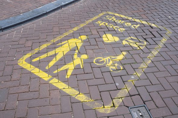 AMSTERDAM, THE NETHERLANDS - AUGUST 30 2020: Yellow signs on the street indicate a Shared Space area in Amsterdam, a concept where priority and rules are lacking for traffic. Focus on the signs door Henk Vrieselaar (bron: shutterstock)
