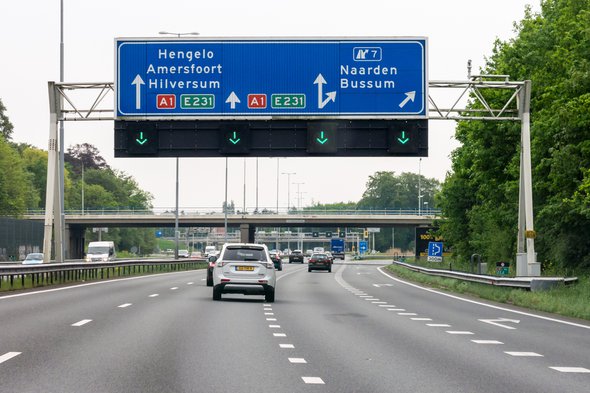 NAARDEN, NETHERLANDS - MAY 10, 2016: Traffic on motorway A1 and overhead route information signs, Naarden, North Holland door TasfotoNL (bron: Shutterstock)