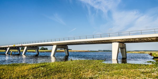 Kampen, The Netherlands, July 29, 2019: new concrete bridge across the Reevediep flood channel of the IJssel river under a blue sky on a summer morning door Frans Blok (bron: shutterstock)