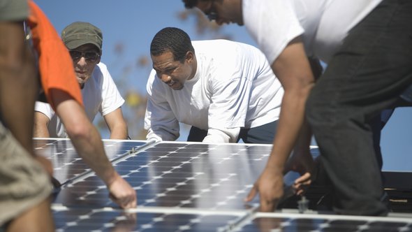 Group of multiethnic engineers placing solar panel on rooftop door sirtravelalot (bron: Shutterstock)