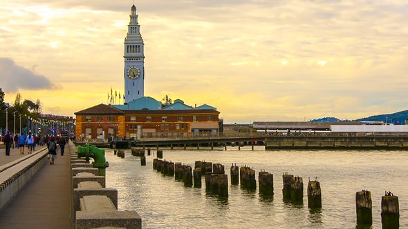 Postcard-like image of the boardwalk/embarcadero leading to the Ferry Building in San Francisco. The sky is highlighted with gorgeous yellow pre-sunset cloud covering. door dlove (bron: shutterstock)