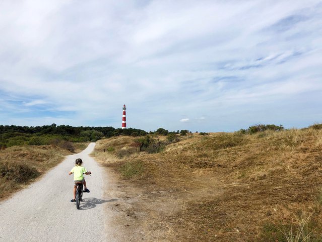 Klein kind fietsend naar de vuurtoren op het eiland Ameland in Friesland, Nederland door Travel Telly (bron: Shutterstock)