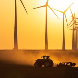 Tractor cultiveert landbouwgrond tijdens zonsondergang bij een rij windturbine. Groningen, Nederland. door Sander van der Werf (bron: Shutterstock)