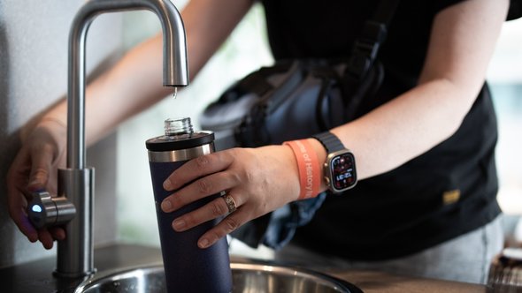 persoon vult een herbruikbare waterfles door LIGHTITUP (bron: Shutterstock)