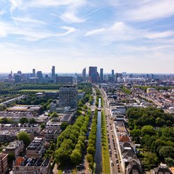 Hoog zicht op de Haagse stad met moderne gebouwen, groene ruimtes, een gracht en geparkeerde auto’s op een zonnige zomerdag in Nederland door 21 Aerials (bron: shutterstock)