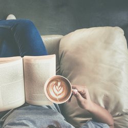 Soft photo of young girl reading a book and drinking coffee door Ko Backpacko (Shutterstock)
