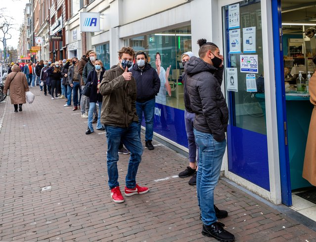 Amsterdam, december 2020: Mensen met een mondkapje in de rij op straat, wachtend om een ​​winkel binnen te gaan. door www.hollandfoto.net (bron: Shutterstock)