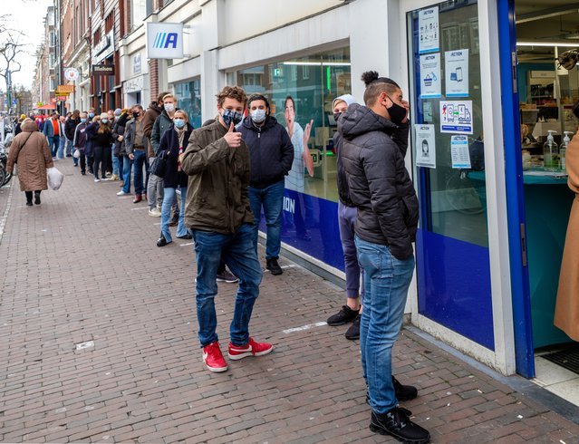 Amsterdam, december 2020: Mensen met een mondkapje in de rij op straat, wachtend om een winkel binnen te gaan. door www.hollandfoto.net (bron: Shutterstock)