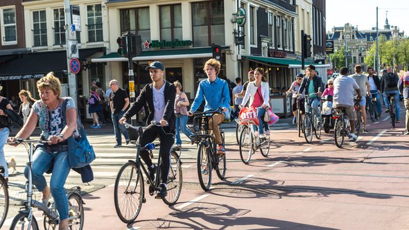 AMSTERDAM, THE NETHERLANDS - JUNE 16, 2016: People riding bicycles in historical part of Amsterdam in a beautiful summer day, The Netherlands on June 16, 2016 door S-F (bron: Shutterstock)