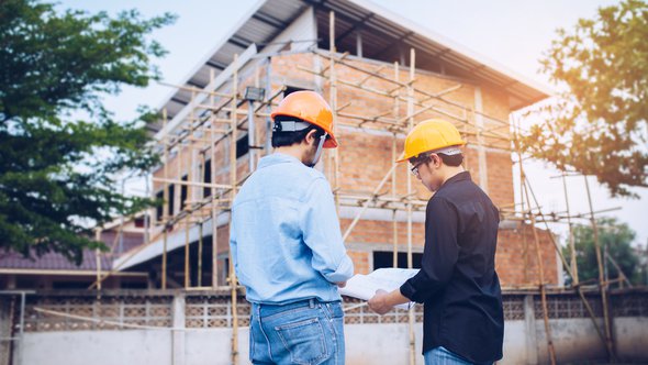 Two engineering man with helmet and paper work are discussing about the project over construction site background. door Freedom Studio (bron: Shutterstock)