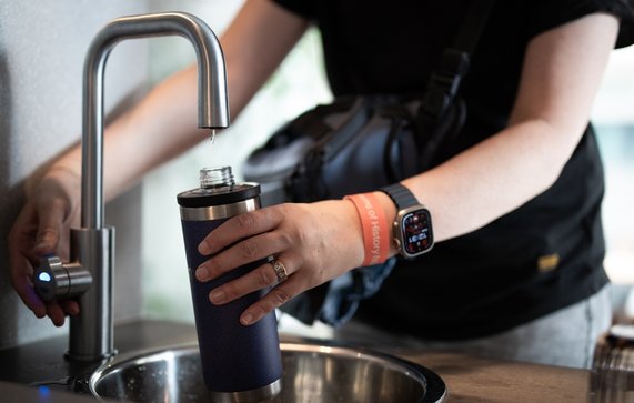 persoon vult een herbruikbare waterfles door LIGHTITUP (bron: Shutterstock)