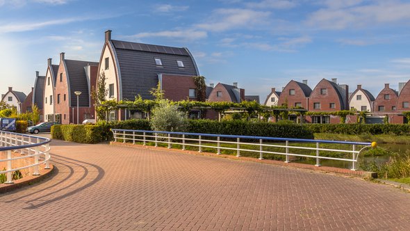 Voorstedelijk gebied met moderne familiehuizen in een kindvriendelijke buurt met bomen en tuinen door Rudmer Zwerver (bron: Shutterstock)