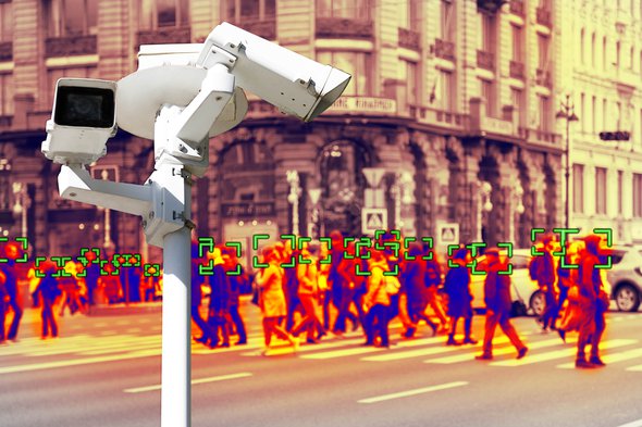 Videobewakingscamera op de achtergrond van mensen die op een voetgangersoversteekplaats lopen. door STEKLO (bron: Shutterstock)