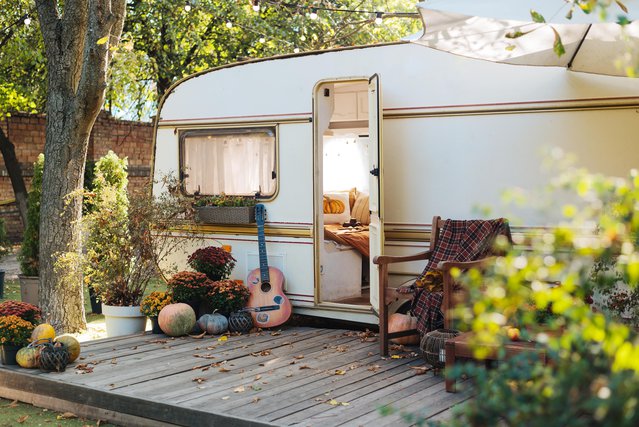 Mobile home van with terrace at sunset in autumn, mobile home, orange fallen leaves. autumn decor, pumpkins door Yarrrrrbright (bron: shutterstock)