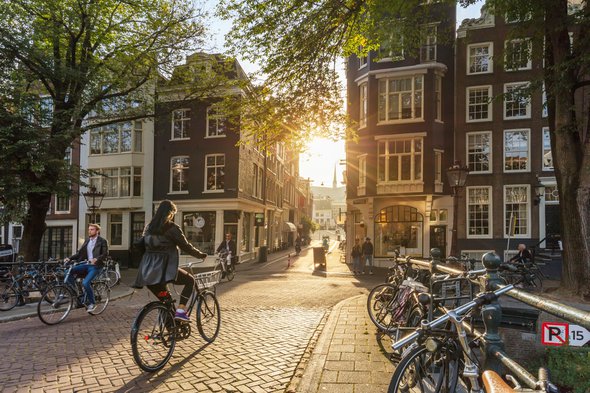 Amsterdam, Netherlands - September 22, 2021: Early morning in Amsterdam. People ride bicycles, the ancient European city of Amsterdam. Sunlight and silhouettes, beautiful downtown door Taiga (bron: Shutterstock)