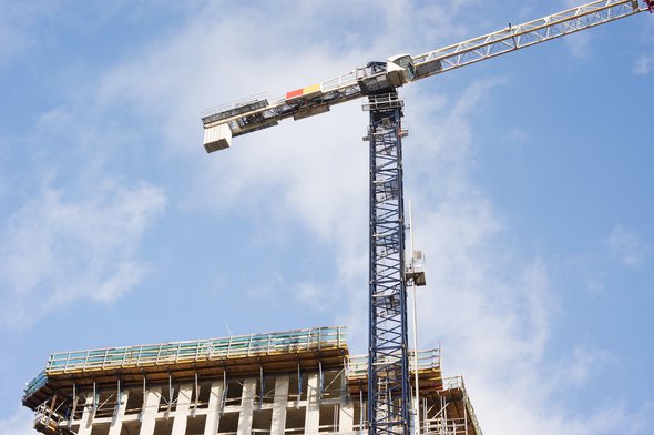 Large residential tower under construction with large blue and white crane on top in Nijmegen in the Netherlands door Marcel Rommens (bron: shutterstock)