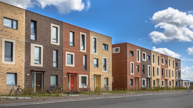 Moderne sociale woningen onder blauwe hemel in terra kleuren met bescheiden familieappartementen in Ypenburg, Den Haag, Nederland door Rudmer Zwerver (bron: shutterstock)