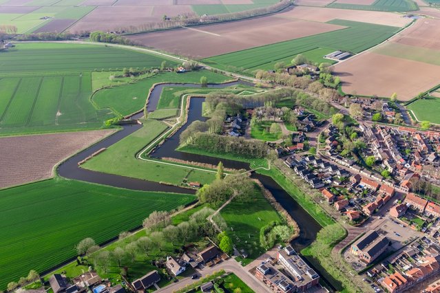 Een drone-luchtfoto van de vestingwerken van Klundert, Noord-Brabant, Nederland, die het stervormige verdedigingssysteem van de stad toont tegen het levendige groen en bruin van het omliggende polderlandbouwland. De hoekige bastions en de verbindende gord door tokar (bron: Shutterstock)